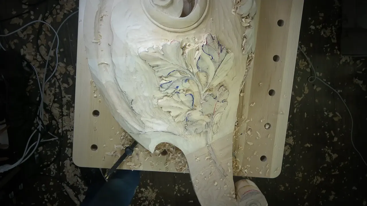 Pale carved block on a drilled bench top, a cluster of oak leaves beside a round opening.