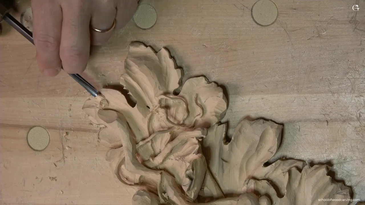 Carved grape leaf with a tool resting at its edge, grain running out across the thin part