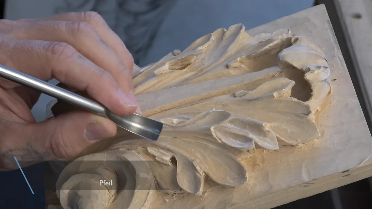 Bright steel spoon bent tool laid along the carved leaf, a faint Pfeil caption showing in the corner