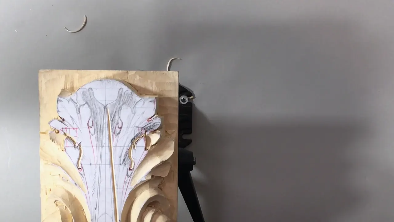 Panel alone on the vise with the drawing still intact and the base volutes already shaped