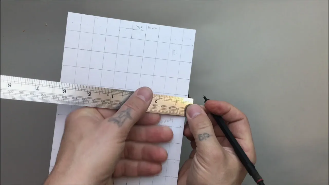 Finished grid of a hundred squares with the steel ruler laid along one edge