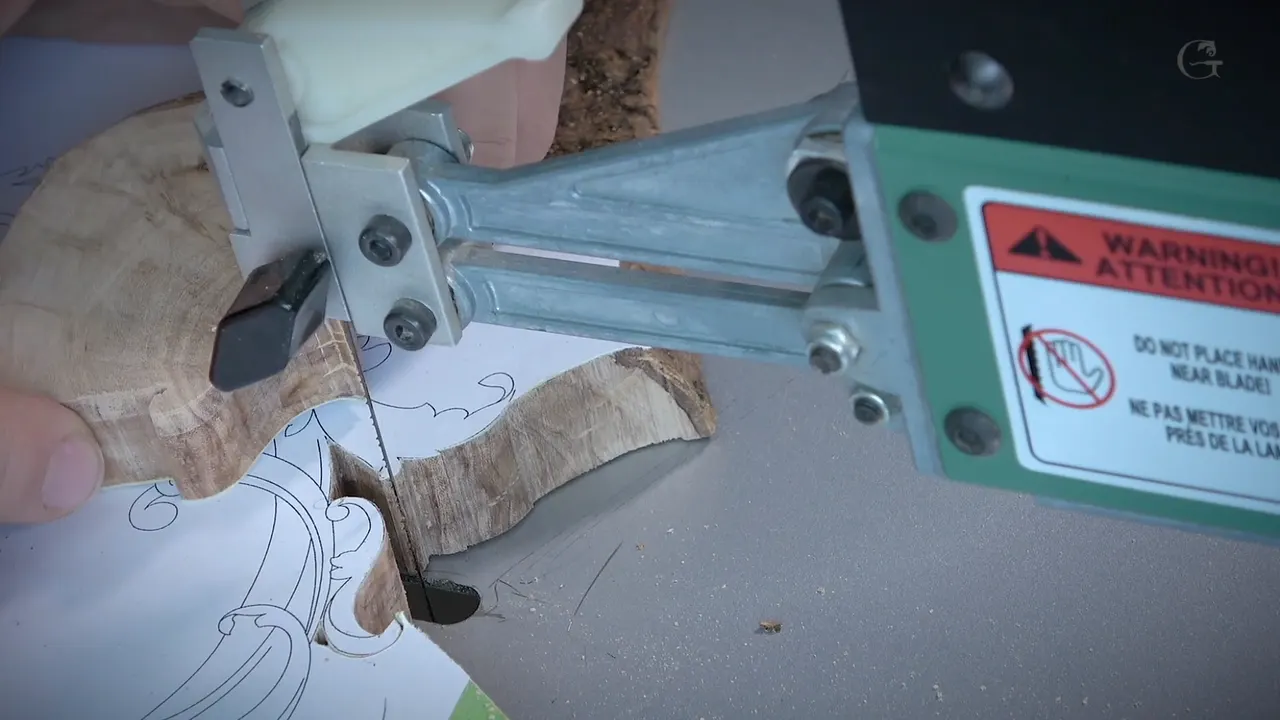 Olive layer under the blade with its paper outline partly sawn, and a warning sticker on the saw arm