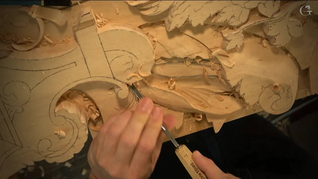 A slim gouge sits in a new groove along a leaf edge, right where it meets a scroll.