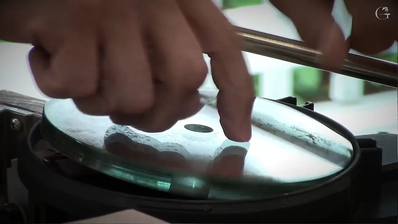 Hands on the flat glass sharpening wheel with the jig bar resting above it