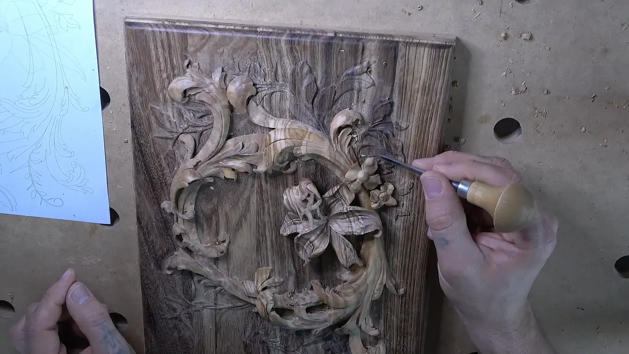 Olive wood lily and small filler flowers on the dark acacia lid, a round handled tool at work beside them