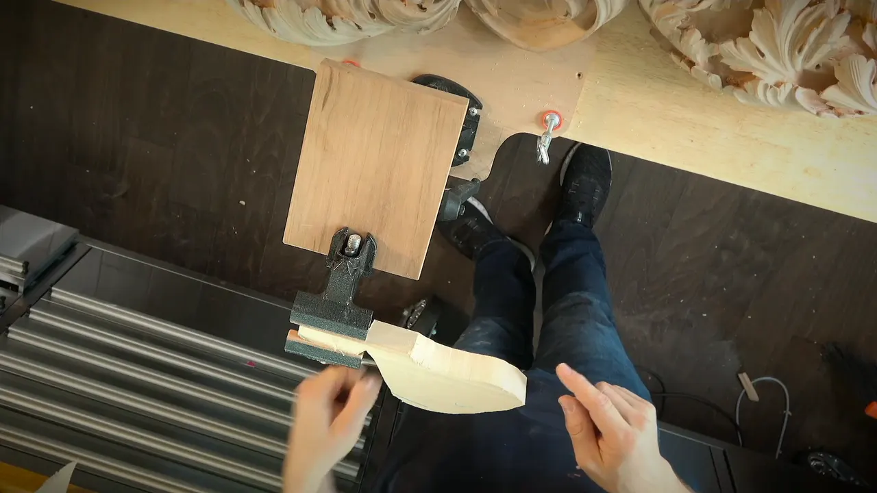 Small basswood piece held by its handle in a clamp vise on a plated block