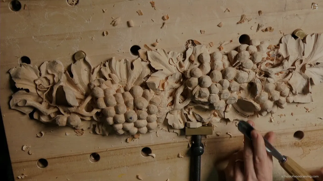 Panel seen from above with the vine running its full length, one hand bringing a gouge in from the right
