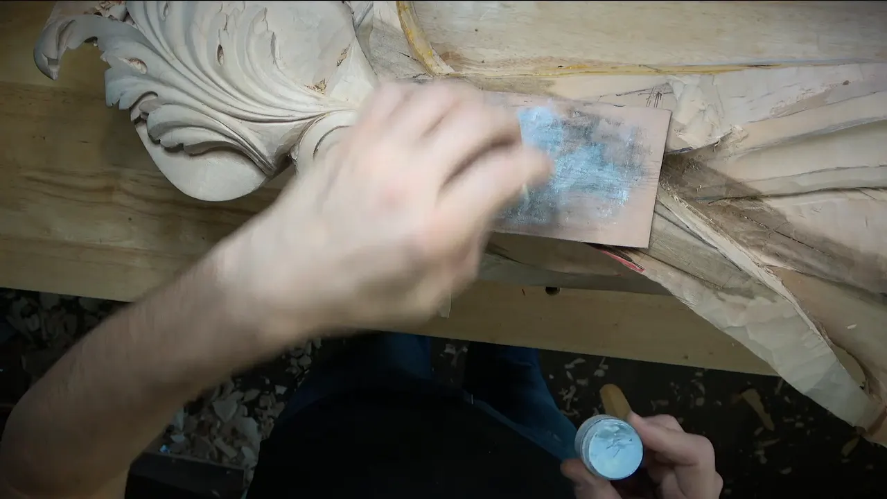 A blurred hand works paste into a piece of leather while the other holds a small white tin