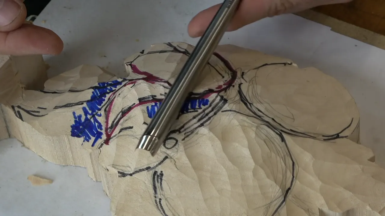 Gouge held point down over the roughed blank, marker lines in two colours running across the wood under it