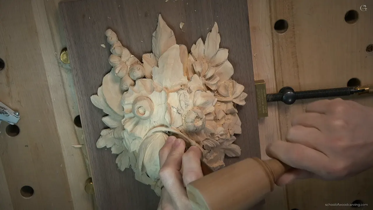 Both hands guiding a Peter Benson detailing tool along the stem of the tulip on the Grinling Gibbons panel