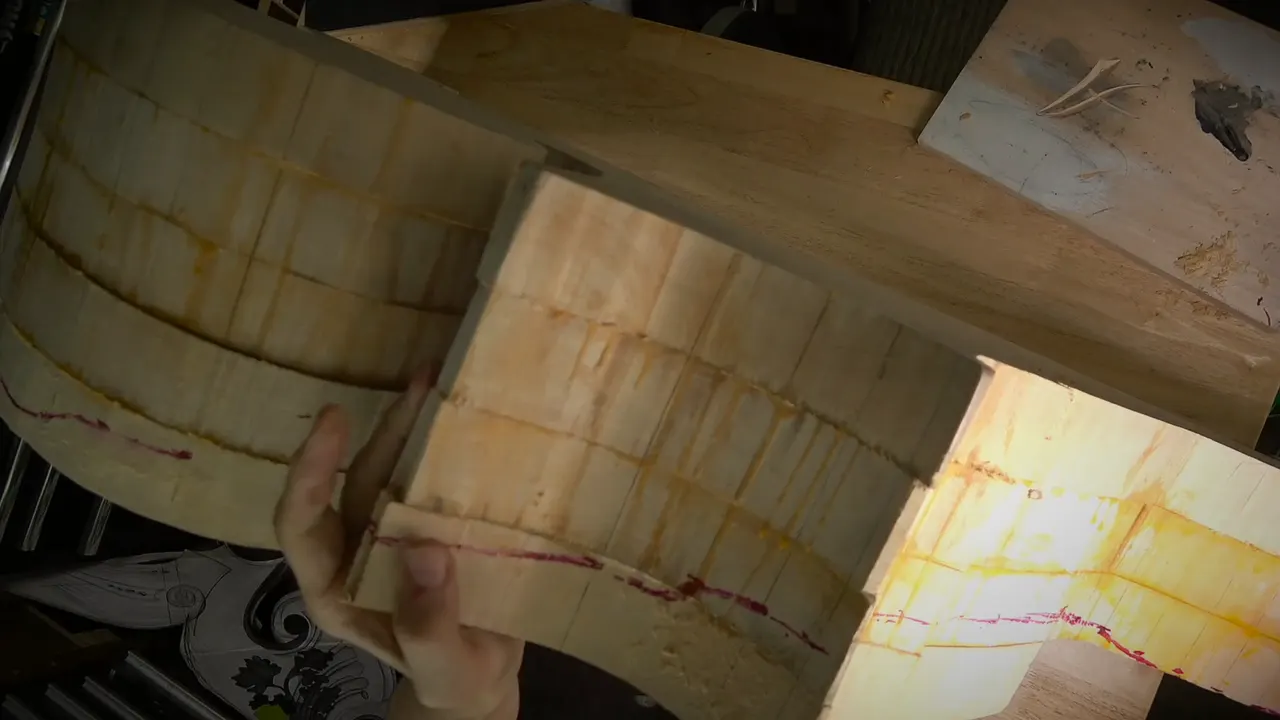 Red marker lines run along the side of a thick block of stacked layers held in two hands