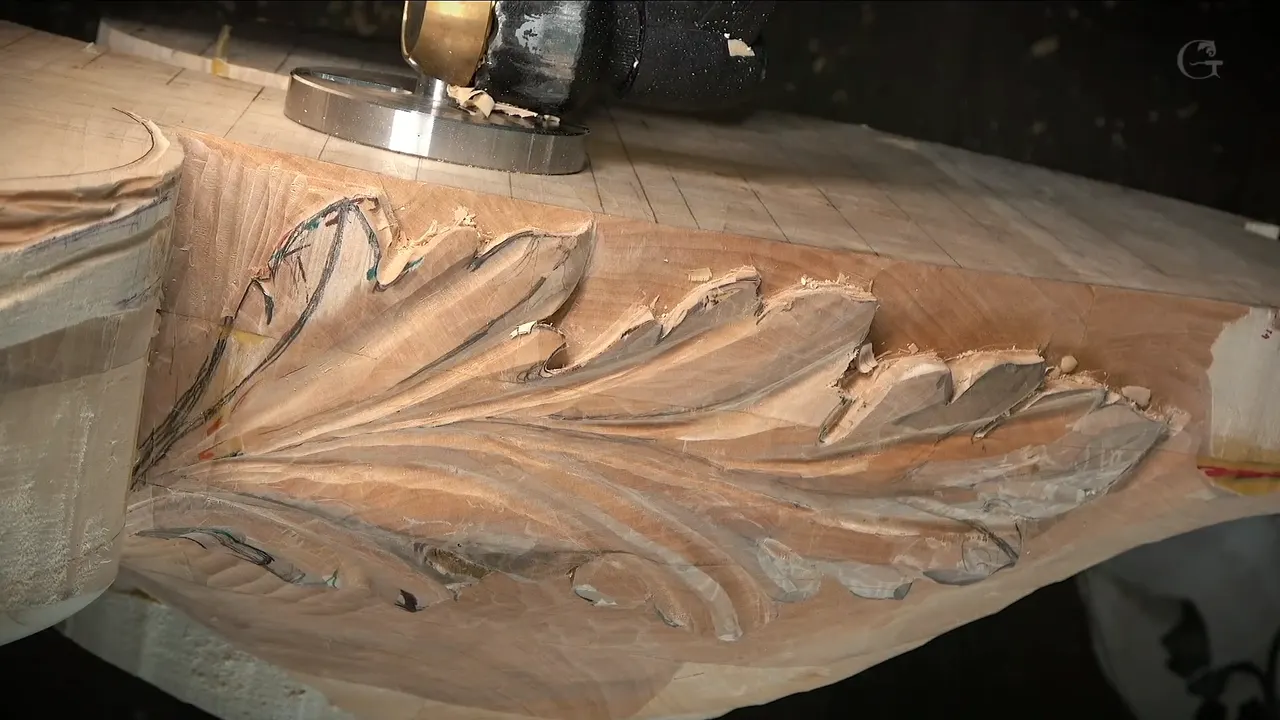 A big acanthus leaf along a thick block, a clamp on the bench above it