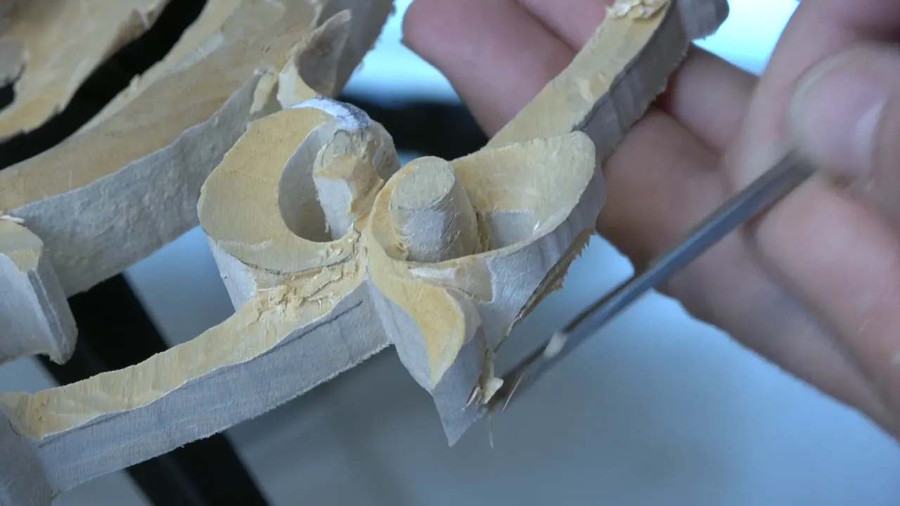 Blade working along the outer rim of the pierced panel, which is standing on edge against its board.