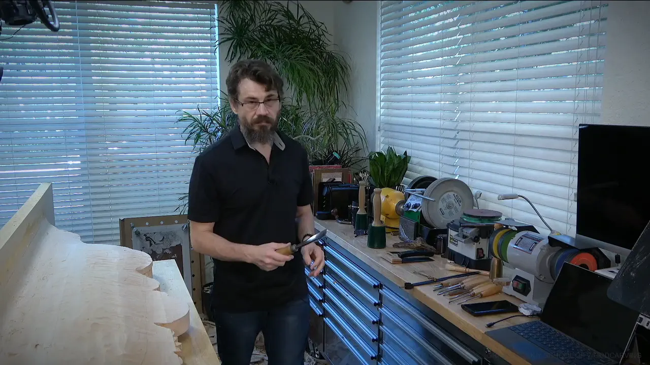 Alexander standing at the ten foot board with a gouge in his hand and the sharpening bench behind him