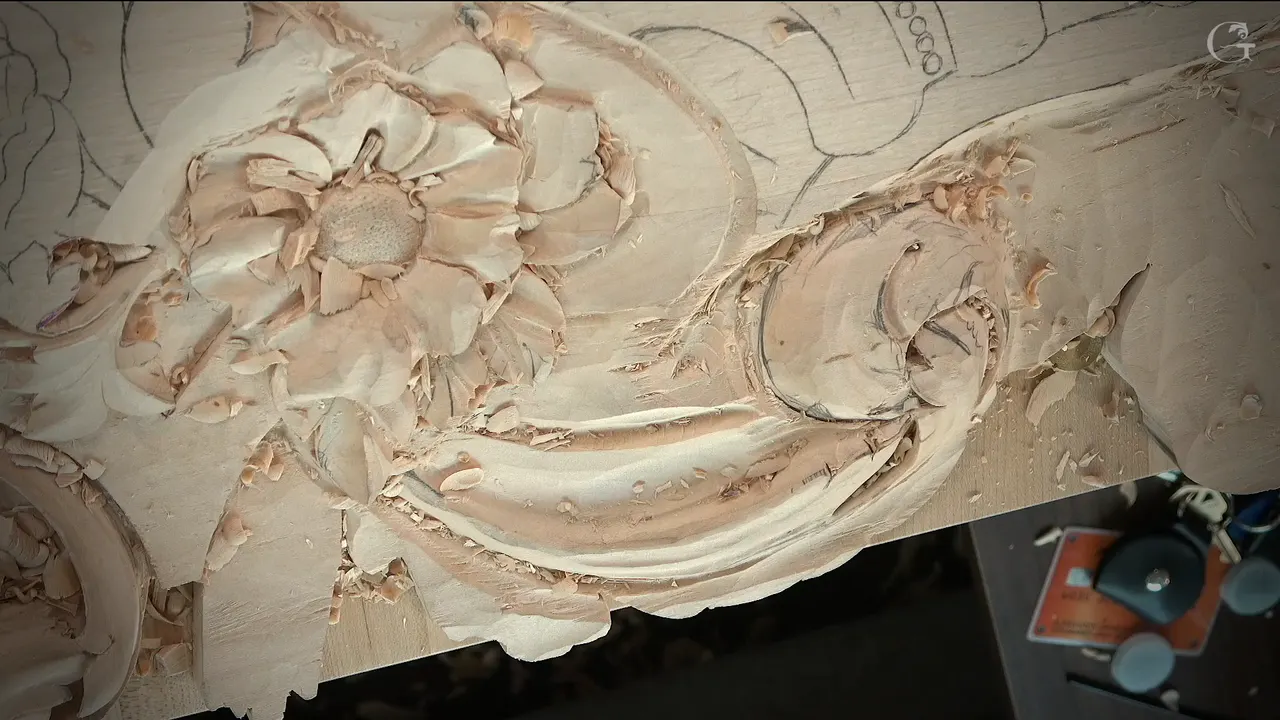 Carved flower and scroll seen from straight above, pencil drawing still on the rest of the board
