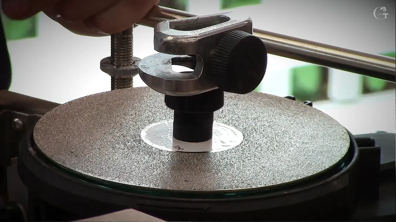 Tormek jig with its big knurled knob stands over a coarse silver diamond disc, the guide bar behind it