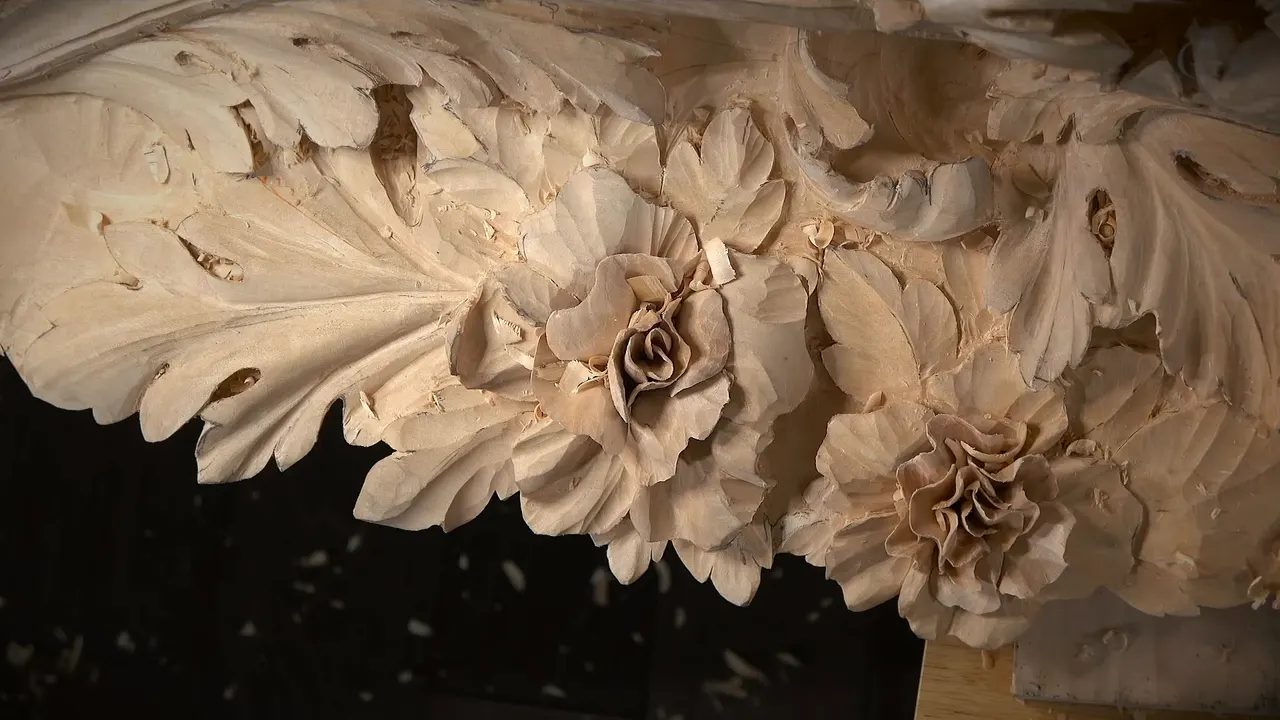 Finished corner of the frieze, a carved rose and a many petalled flower sitting among acanthus leaves