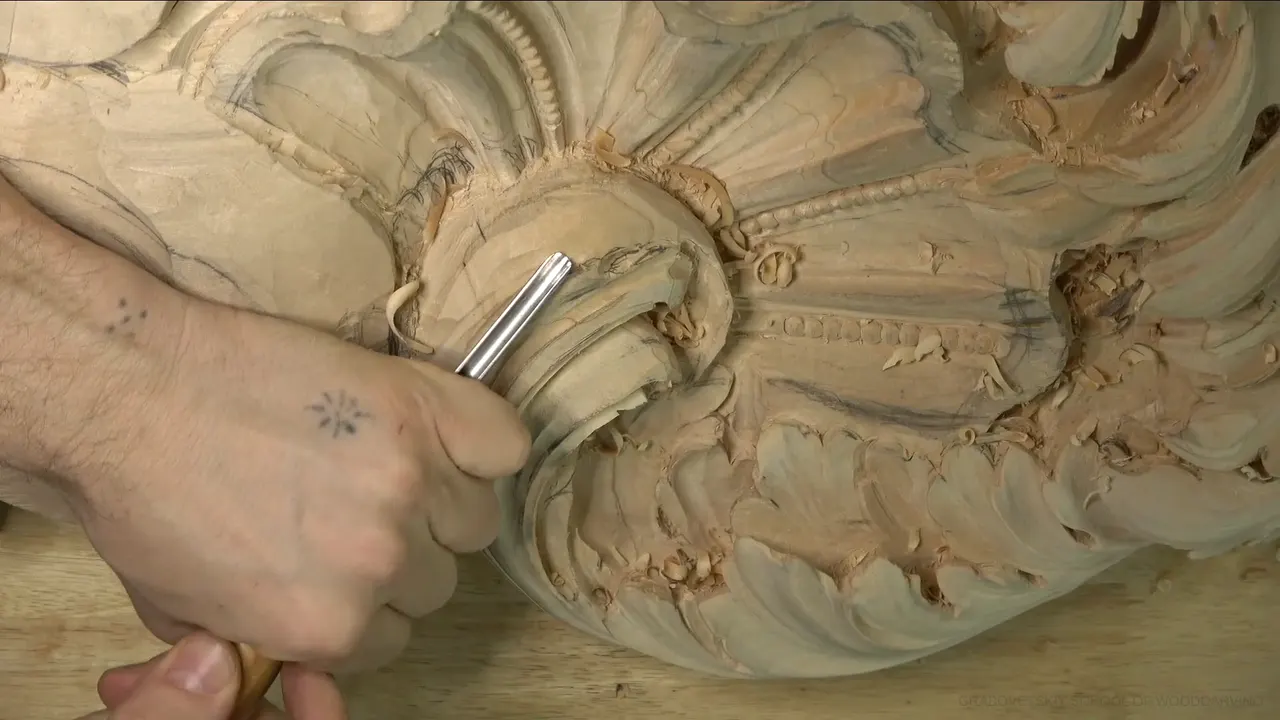 Lime acanthus head with a beaded shell on top and a gouge working the curl below.