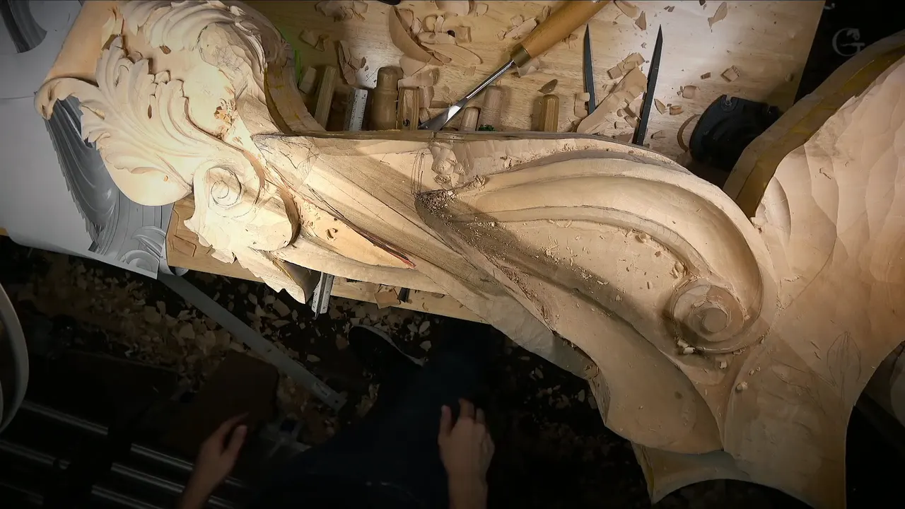 Whole rough carving across the bench, a leafy head at one end, gouges lined up behind
