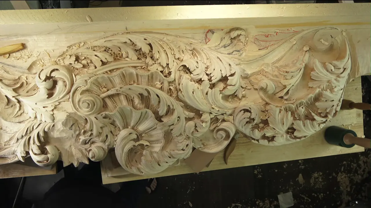 Overhead view of the Venetian acanthus frieze, shavings everywhere, a green mallet resting at the bottom edge.