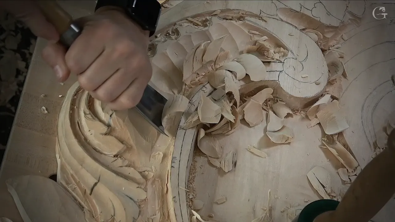Wide gouge in a right hand beside the carved curl, big chips lying in the curve