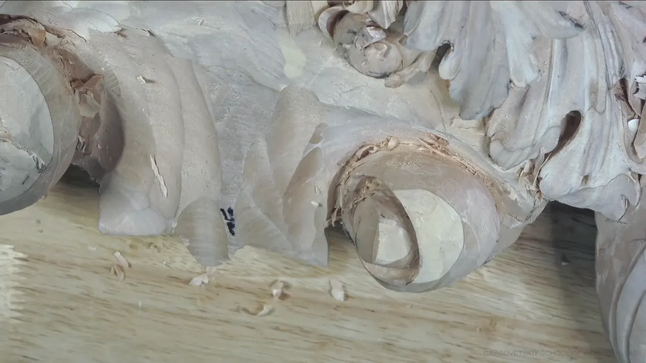 Looking down into the round end of a carved scroll, with a ring of shadow around its pale middle.