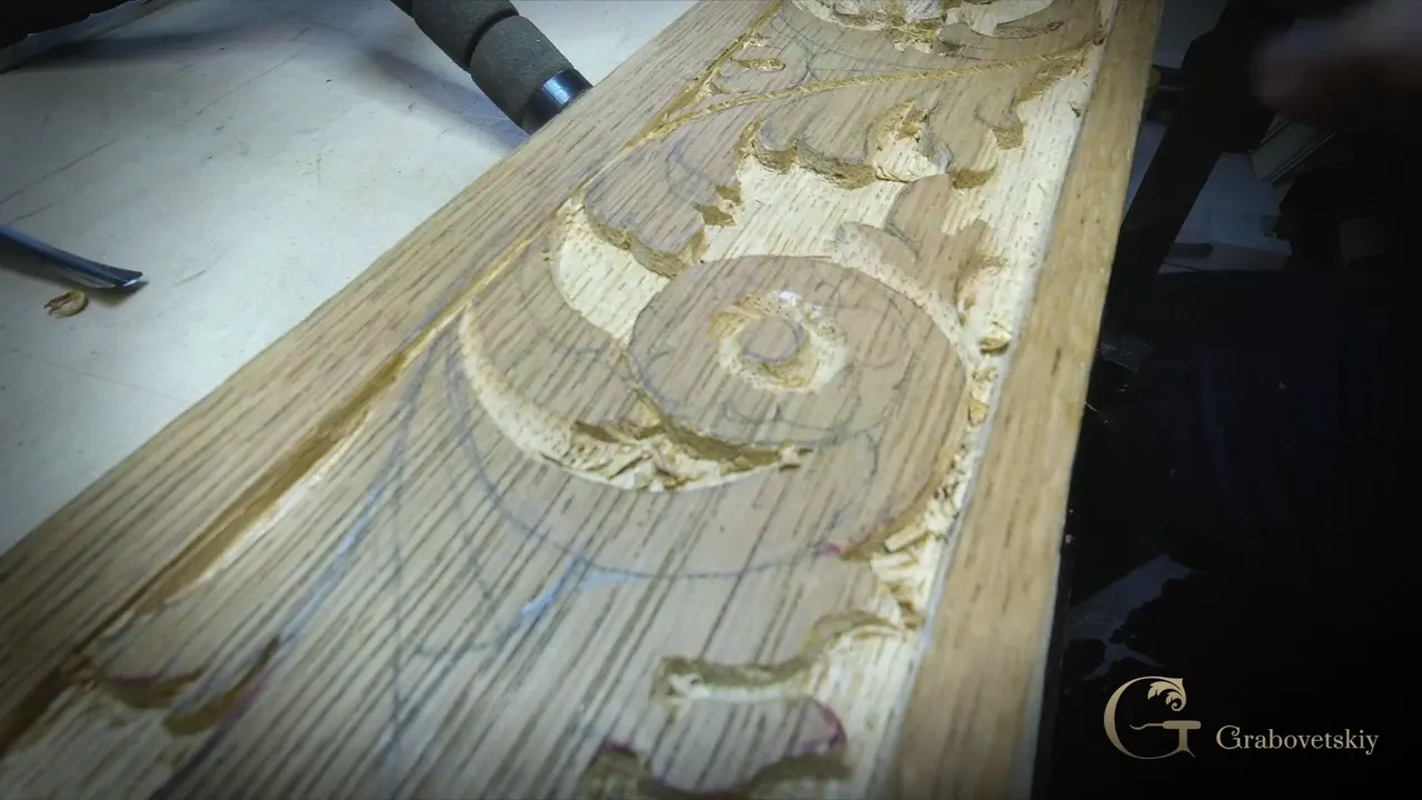 Oak apron length with a round flower inside a carved ring and leaves around it, pencil lines still on the wood