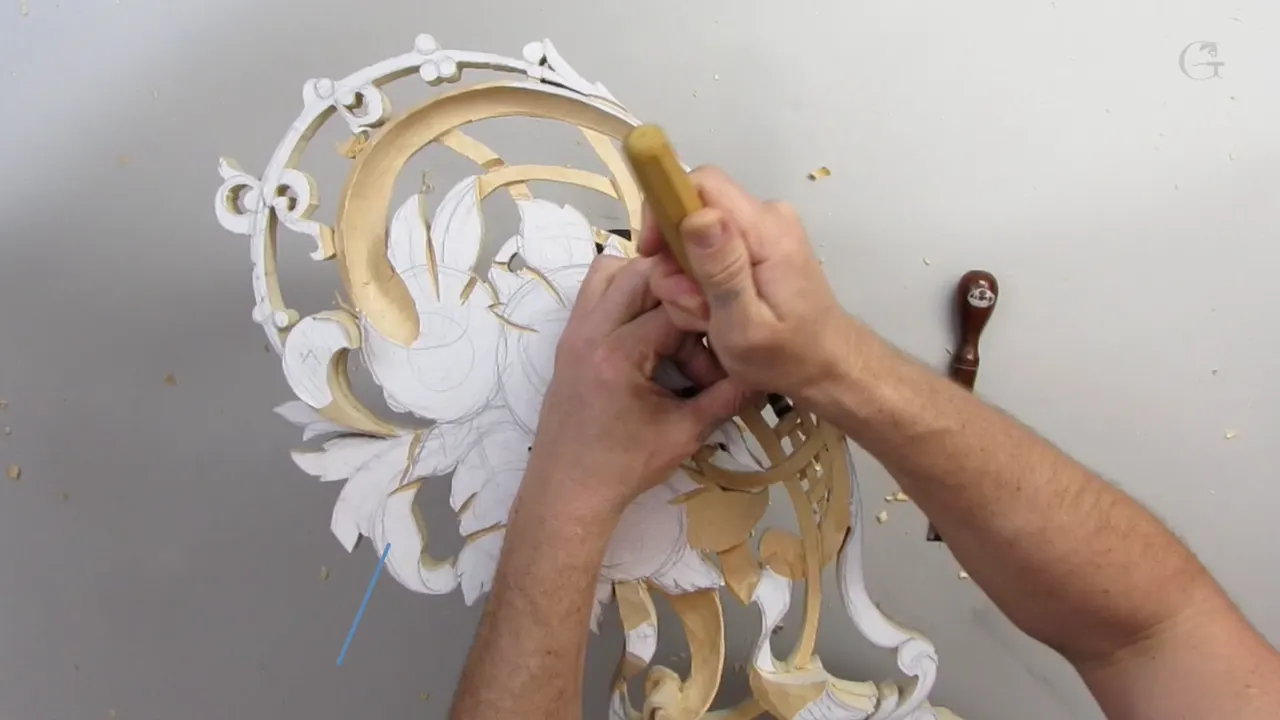 Two hands hold one tool upright over the oval, its scrolls painted white.