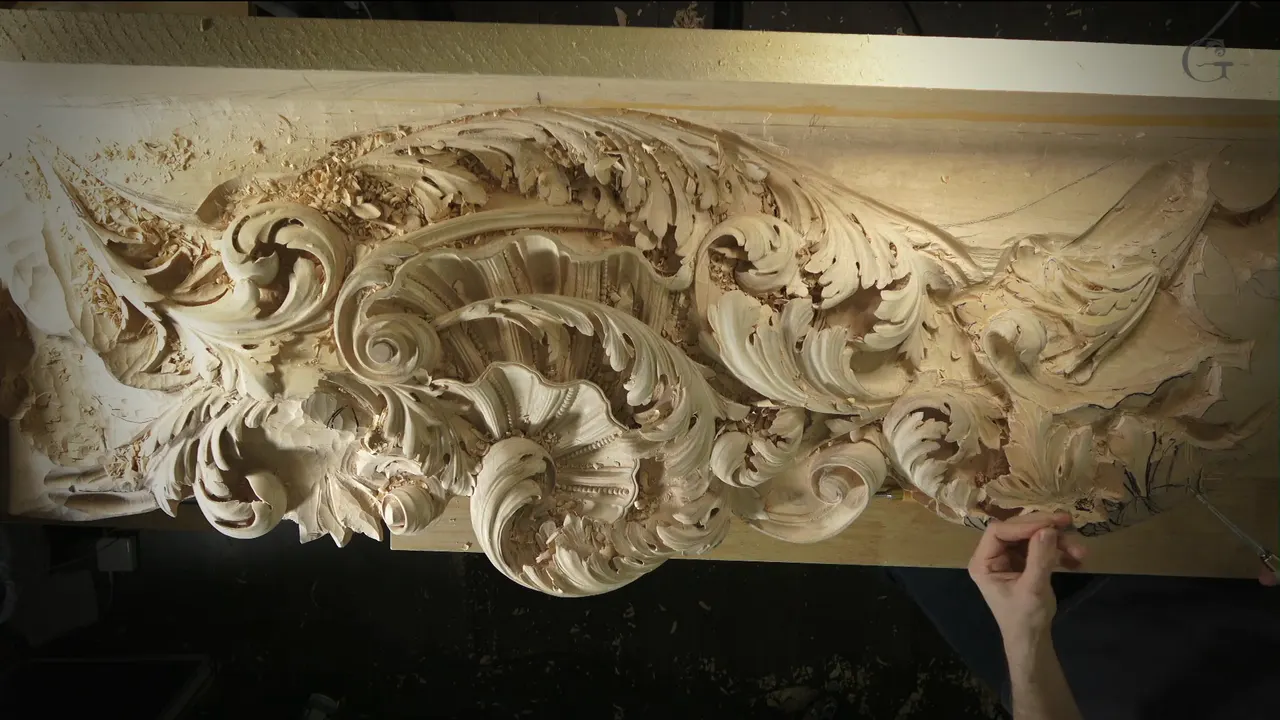 Overhead view of the long Venetian acanthus section in bare limewood, with one hand at its edge