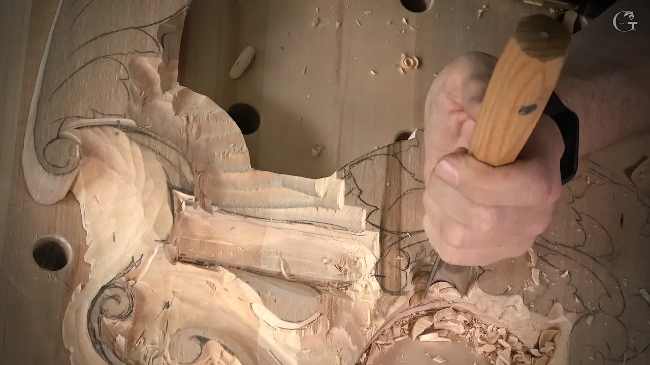Gouge chopped straight down into a section being lowered beside a carved scroll