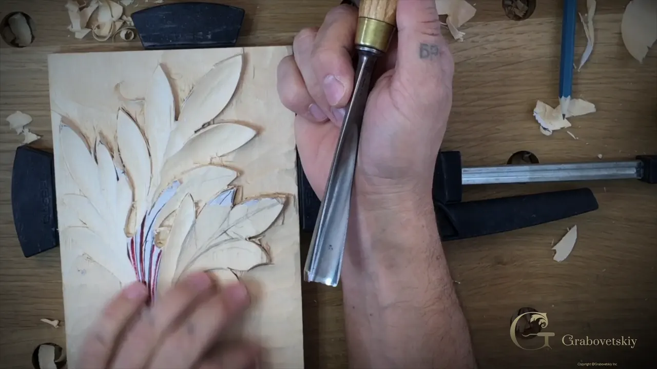 From above, the acanthus panel clamped down with a gouge in the right hand