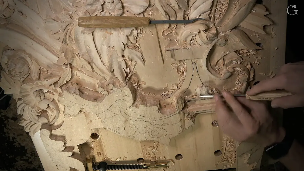 A small veiner held at the molding, with the whole carved panel spread out around it