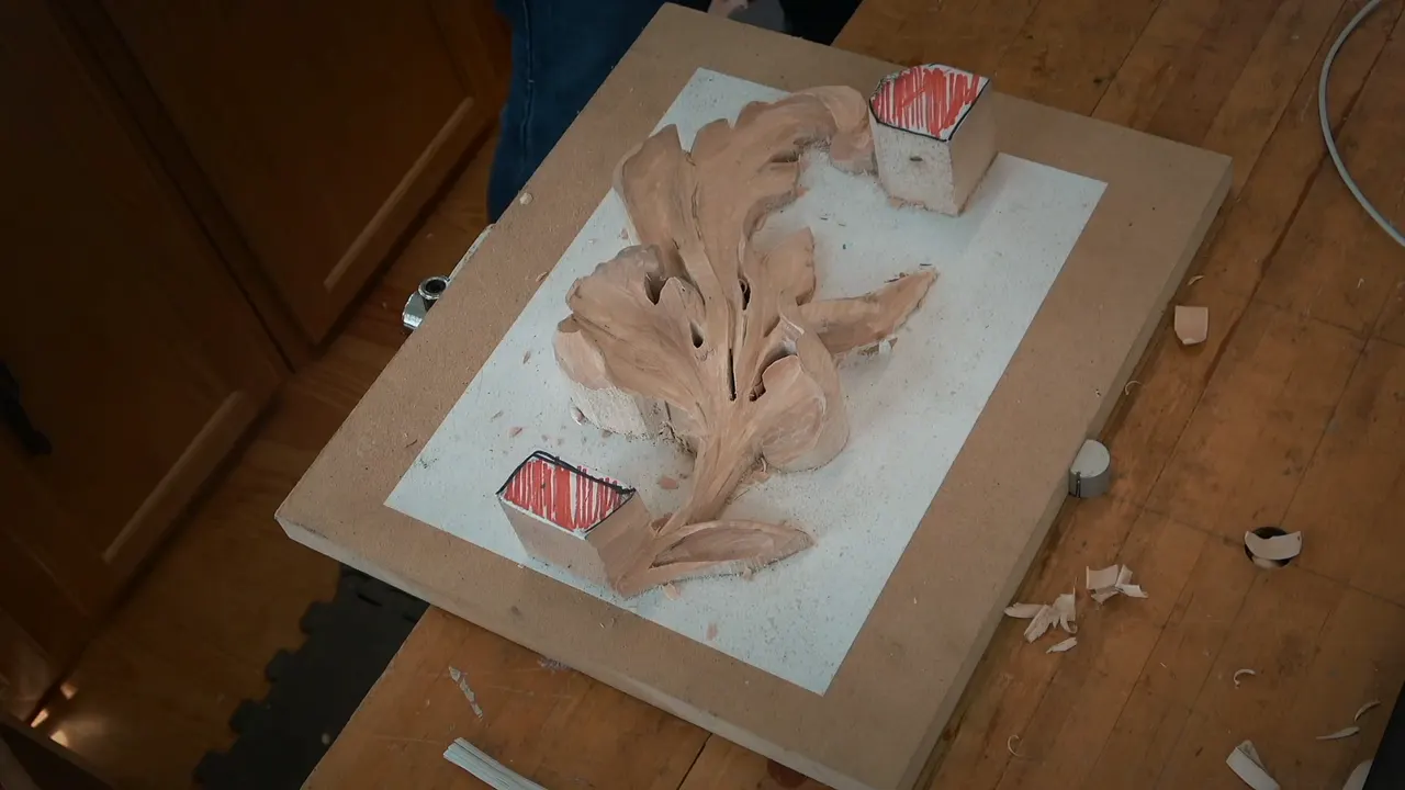 Top view of the acanthus leaf on its board, two tabs marked red still holding it down