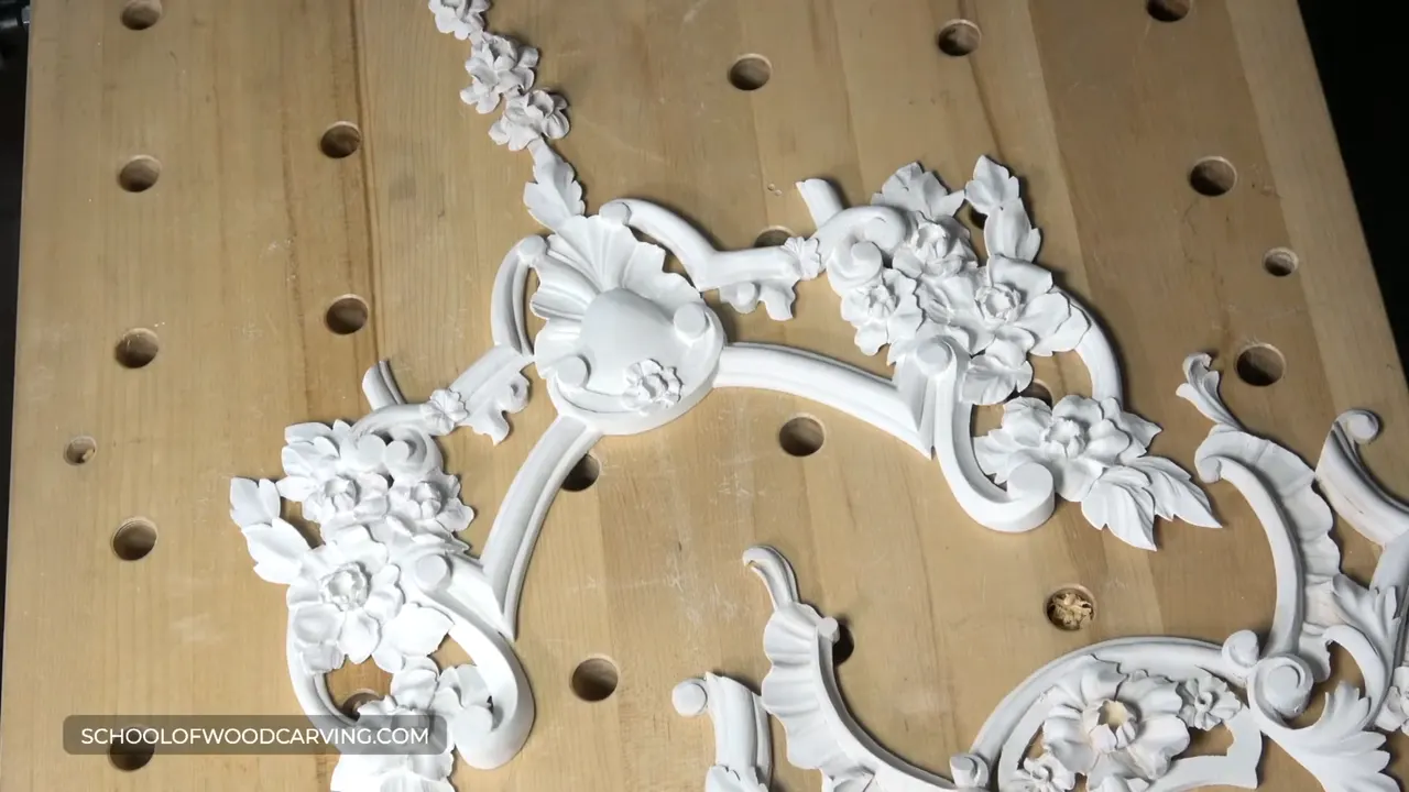 White painted carvings laid out on a bench full of holes