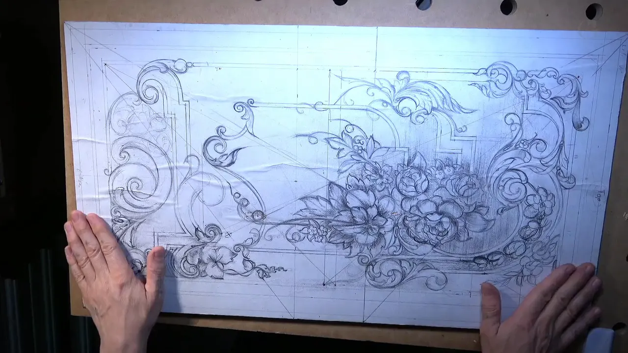 Both hands steady the pencil drawing of the whole panel on its board