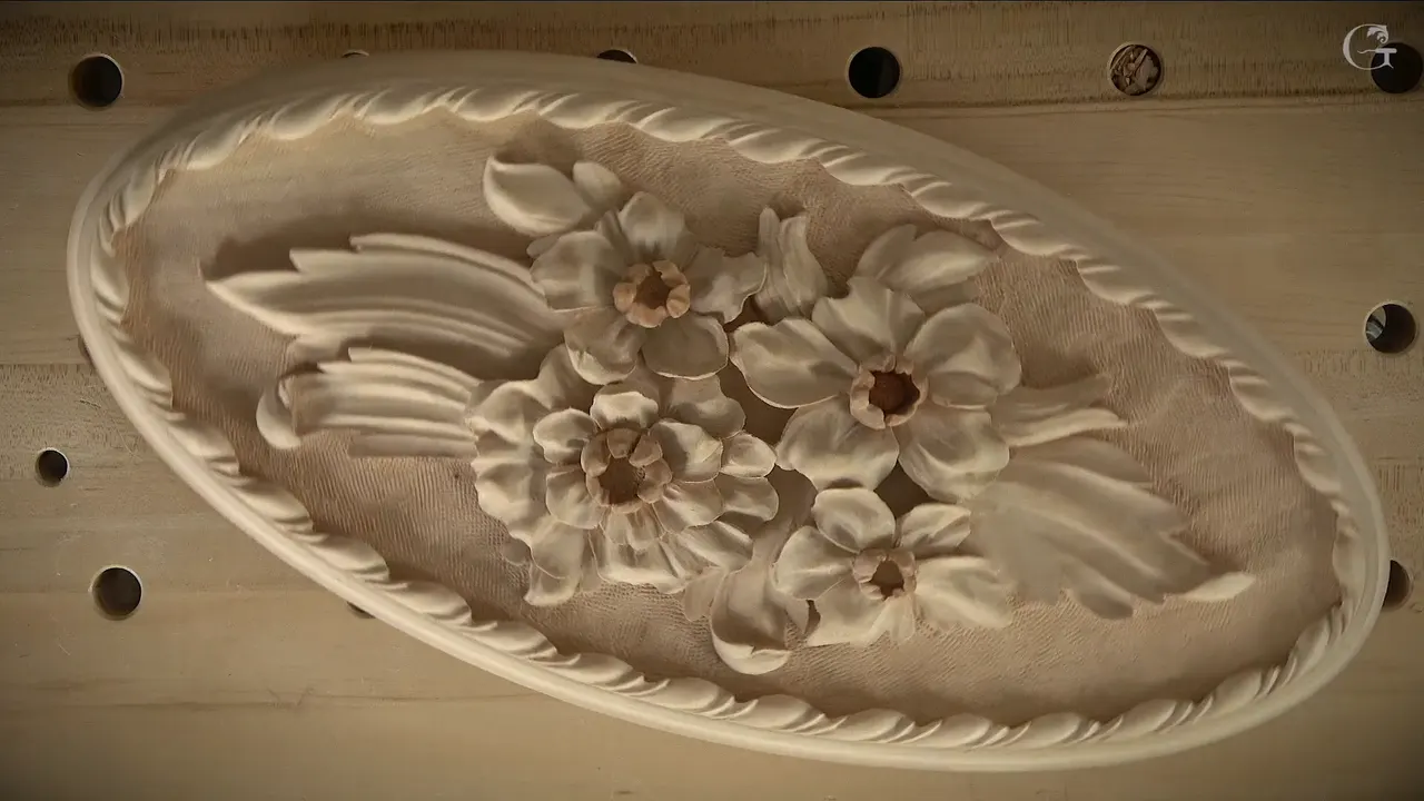 The finished oval, its carved border circling the flowers on a textured ground