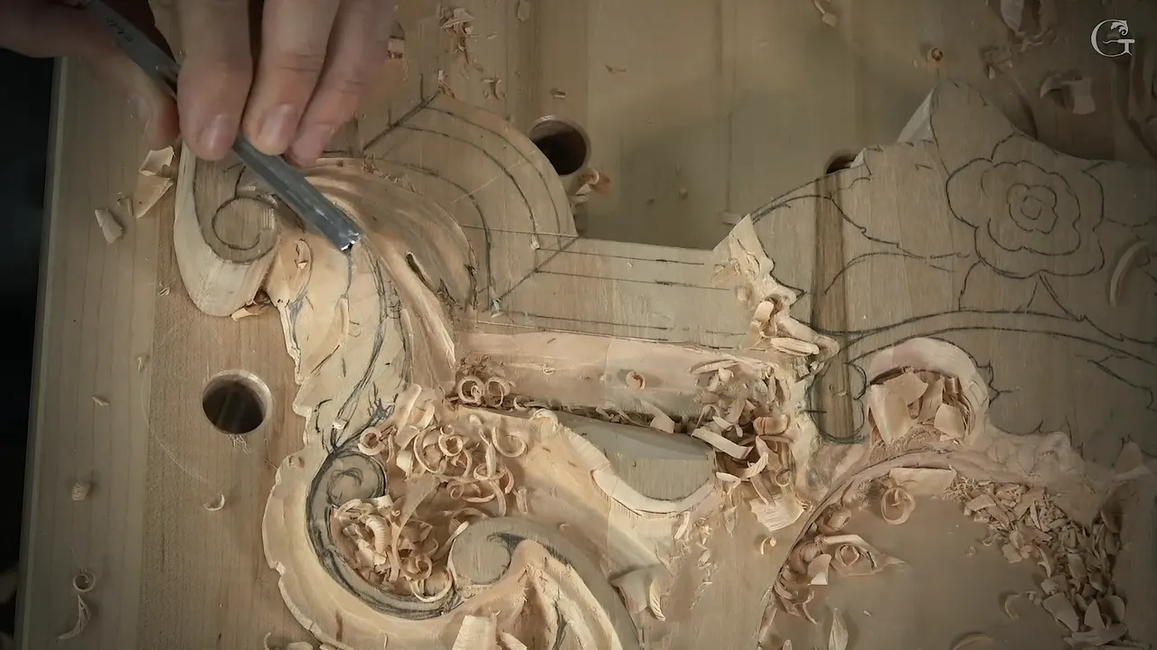 A narrow gouge in one hand fans fresh grooves across the lobes of an acanthus leaf